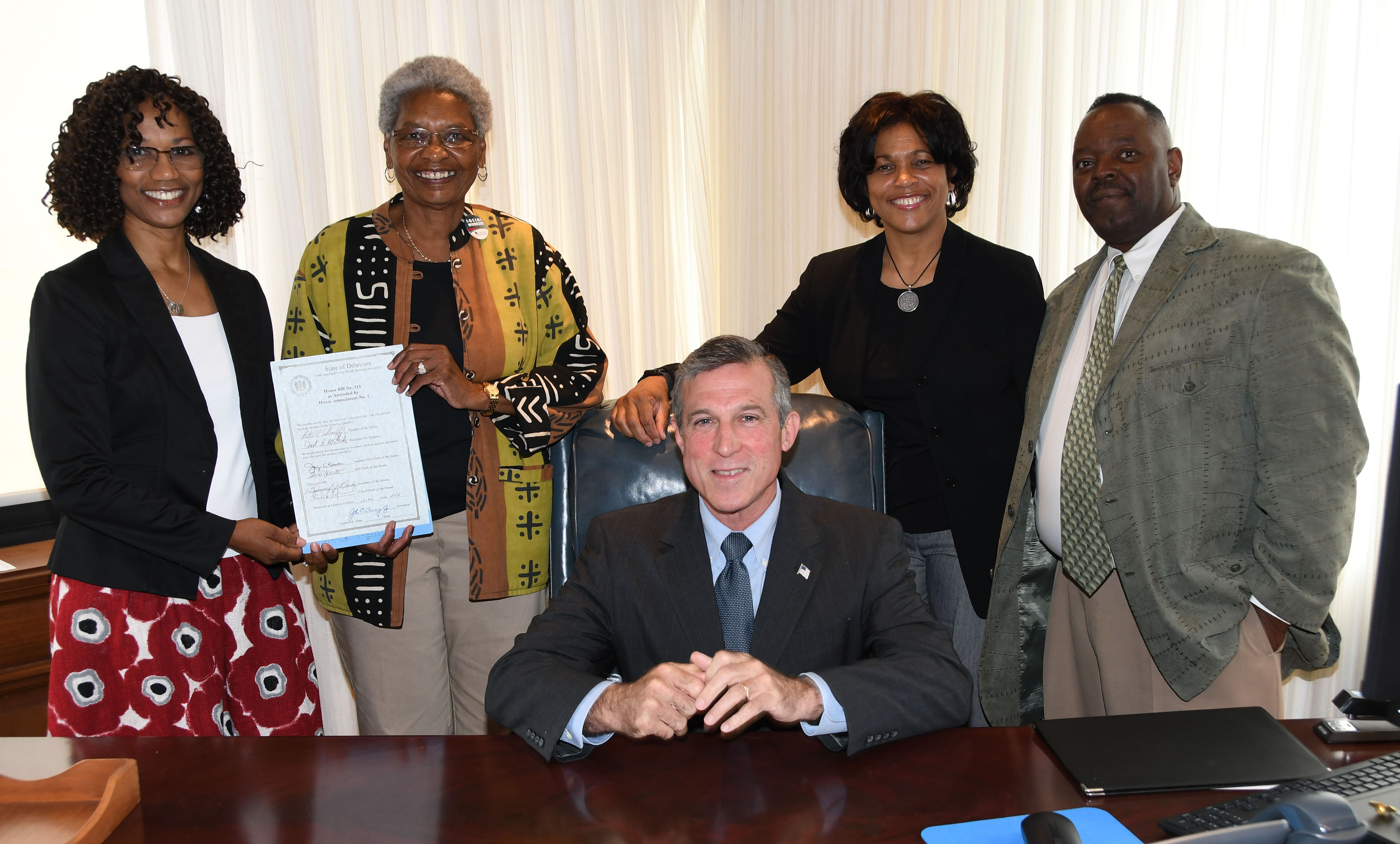 Gov. John Carney poses with the NASW-DE subcommittee -- all DSU folks -- who were instrumental in the passage of HB 311. Standing from l-r: Dr. Sheridan Kingsberry and Dr. Marlene Saunders holding the signed legislation, along with Dr. Fran Franklin and Philip Thompson.