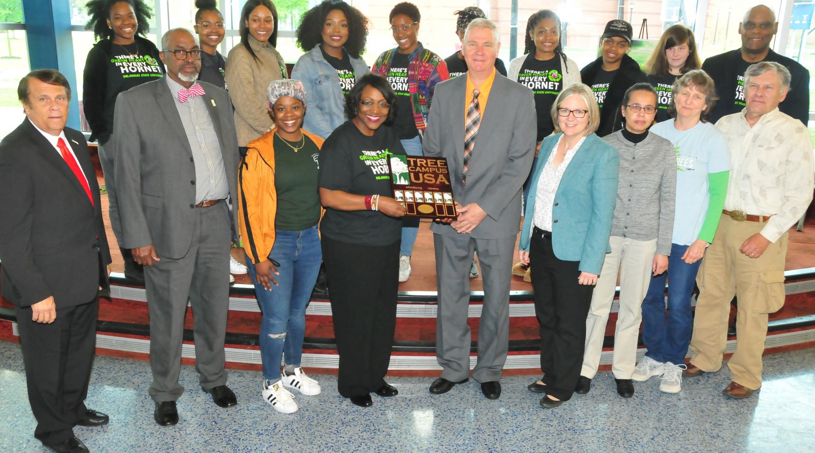 <p>Dr. Vita Pickrum (center) receives the Tree Campus USA renewal designation on behalf of DSU from Dr. Michael Valenti, Delaware state forester. They are flanked by other DSU officials and Roteract and Interact student organizations.</p>