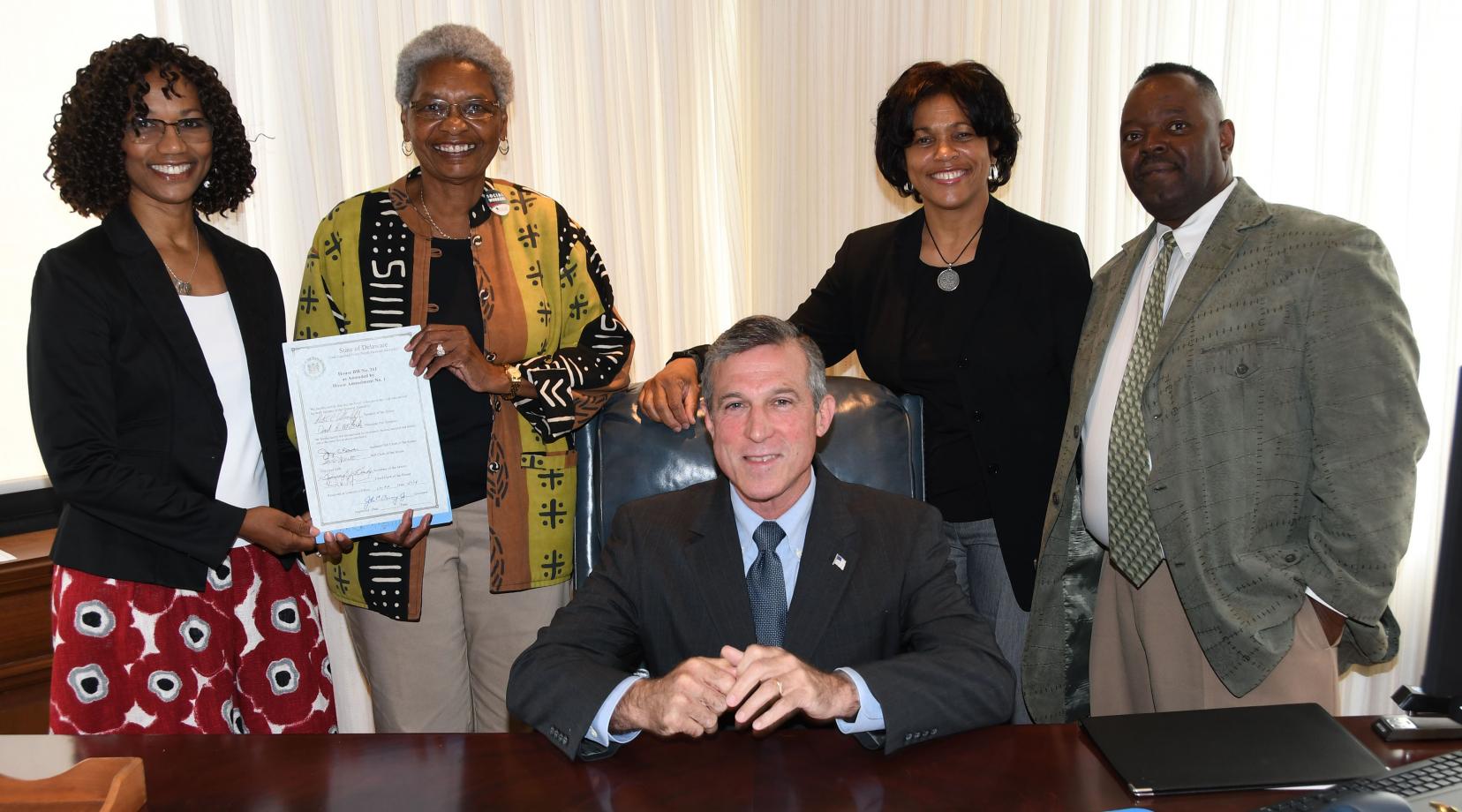 Gov. John Carney poses with the NASW-DE subcommittee -- all DSU folks -- who were instrumental in the passage of HB 311. Standing from l-r: Dr. Sheridan Kingsberry and Dr. Marlene Saunders holding the signed legislation, along with Dr. Fran Franklin and Philip Thompson.