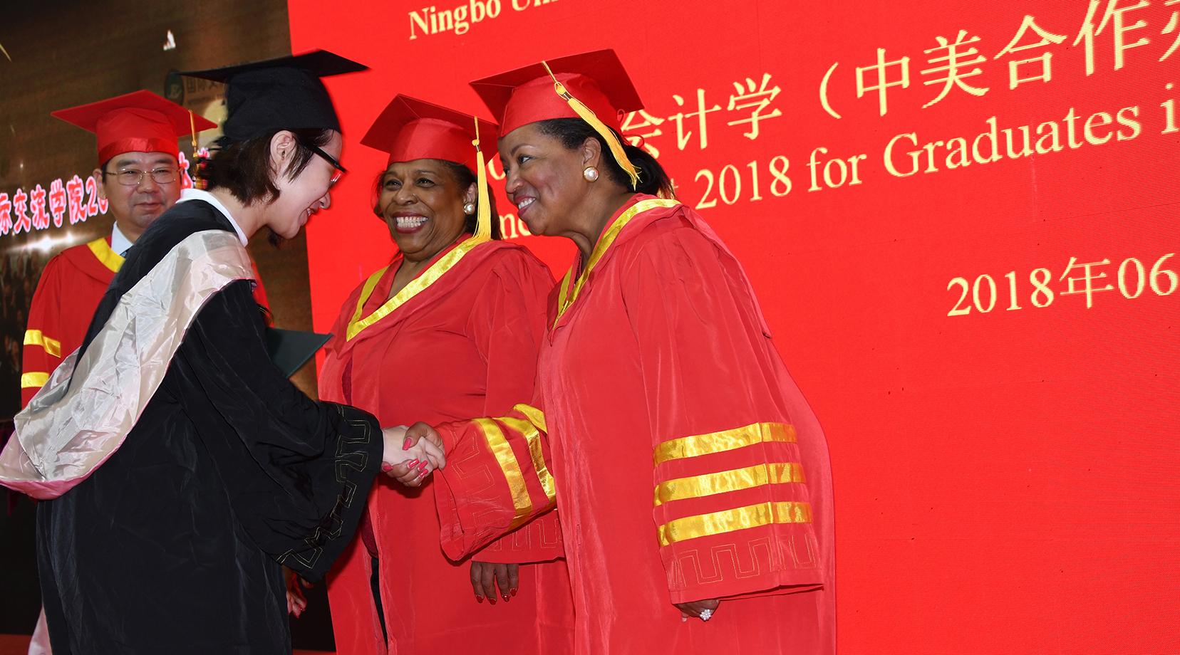 Dr. Wilma Mishoe and Dr. Devona Williams congratulate a graduate during the Commencement ceremony.