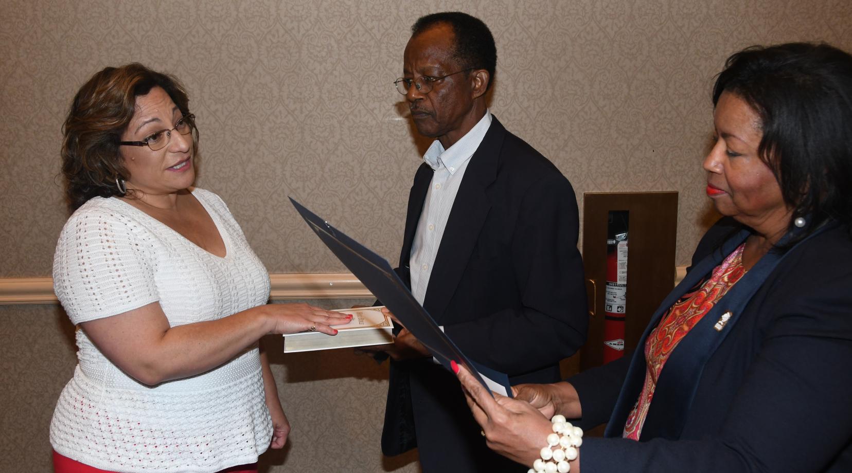 <p>New Board of Trustees member Margie Lopez Waite (l) is sworn in by Board Chair Dr. Devona Williams during the Sept. 20 meeting. Trustee Harold Stafford holds the bible.</p>