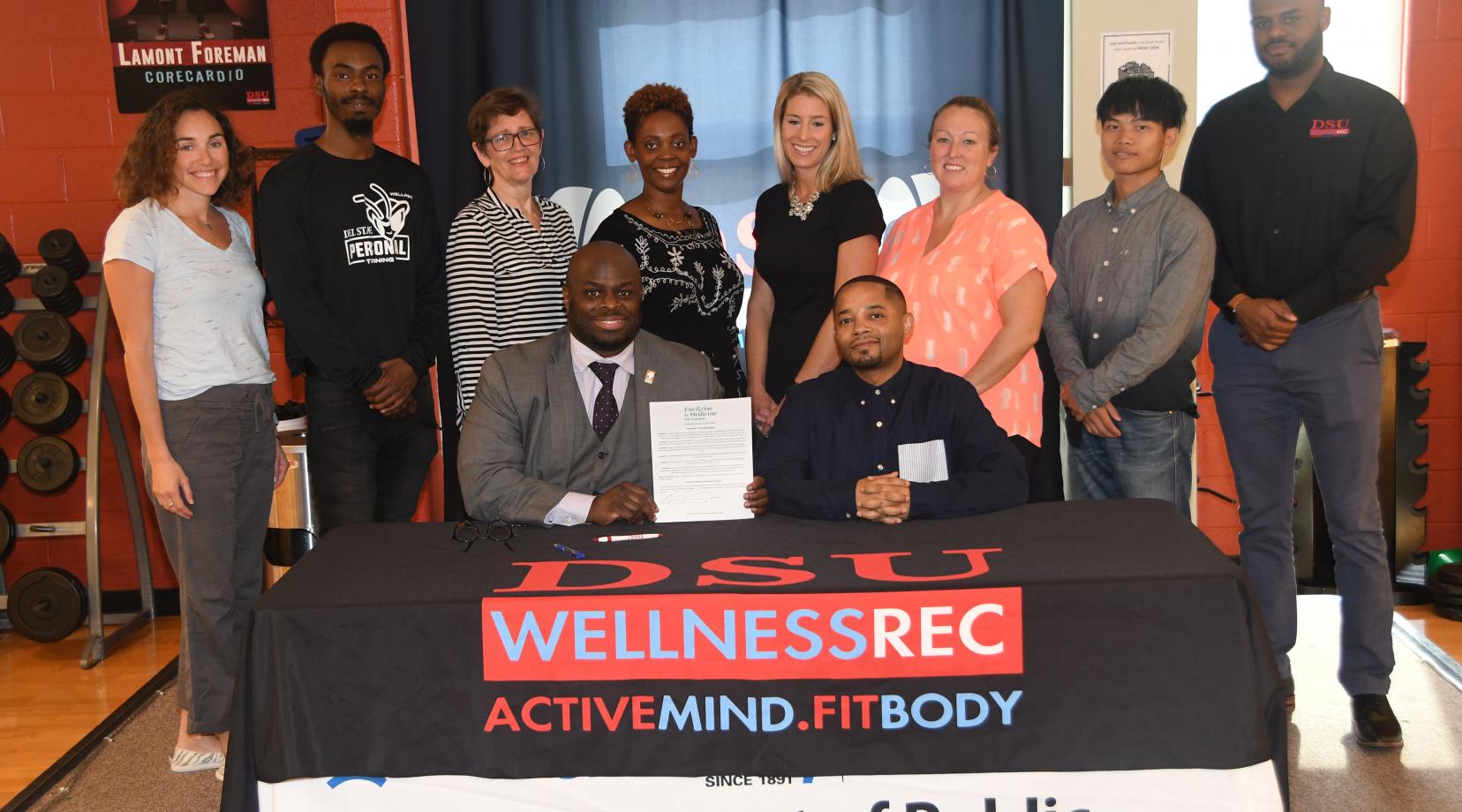 University Provost Tony Allen, with Public and Allied Health Chair Dr. Chris Mason beside him and flanked by department members, WRC staff and other health enthusiasts, hold up the proclamation he just signed declaring that October is Exercise is Medicine Month on campus.