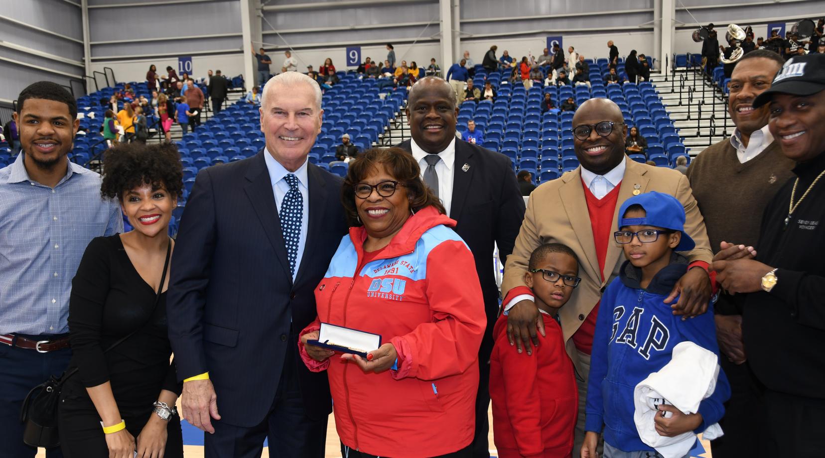 Dr. Wilma Mishoe stands next to Wilmington Mayor Michael Purzycki as she is honored by the city as part of their annual Black History Month celebration at the 76er Fieldhouse as part of the Long Island Nets vs. Delaware Blue Coats basketball game. Standing around them are city officials and DSU community members.