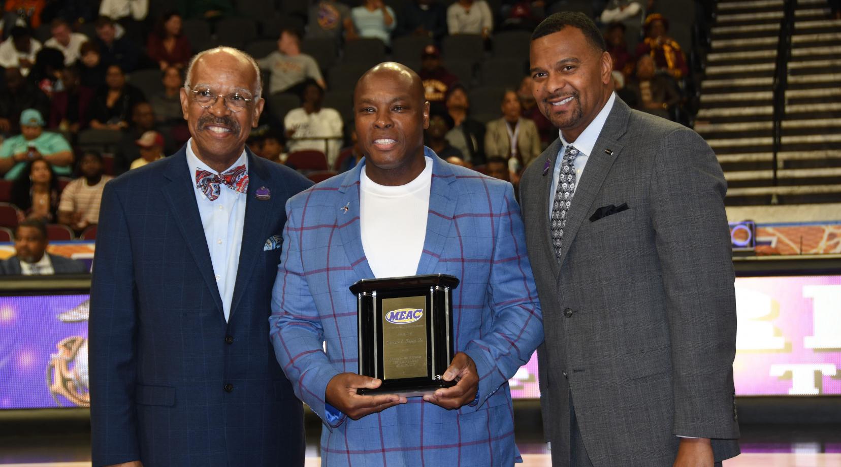 Delaware State University's 2019 Distinguished Alumnus of the Year Ronnie Shaw Sr. (center), receives the award from Dr. Irving H. Smith (l), president of the MEAC Delegate Assembly, and James Church of Priority Automotive, tournament sponsor.