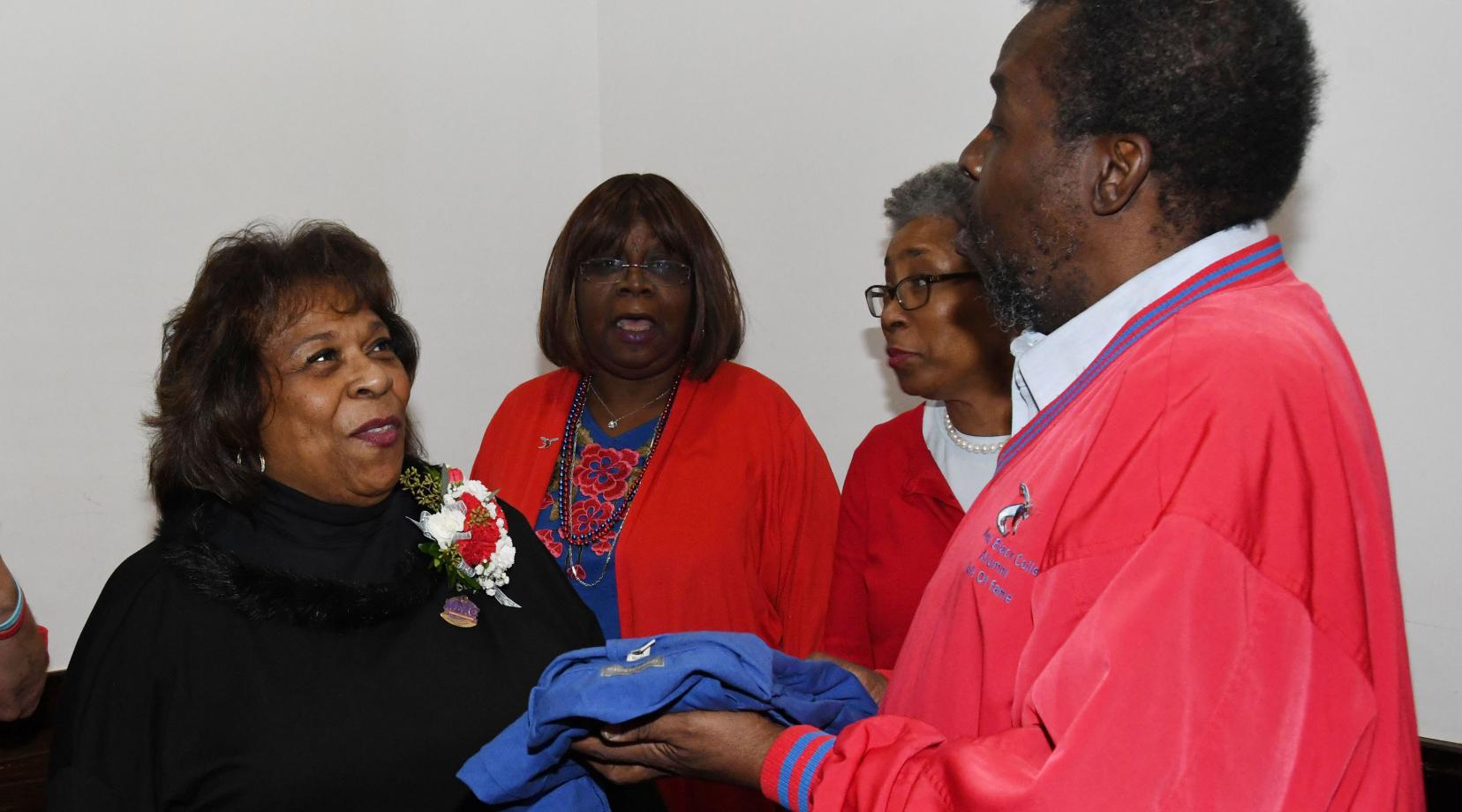 <p>Alumnus Albert Weal (r) presents University President Wilma Mishoe with an alumni shirt during a dinner gathering during the MEAC Tourney.</p>
