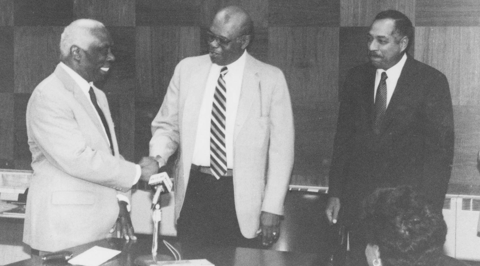 The historic 1987 passing of the presidential torch between then-outgoing DSC President Luna I. Mishoe (l) and his successor Dr. William B. DeLauder (r). Then-Board of Trustees President William Dix (center) shakes Dr. Mishoe's hand.