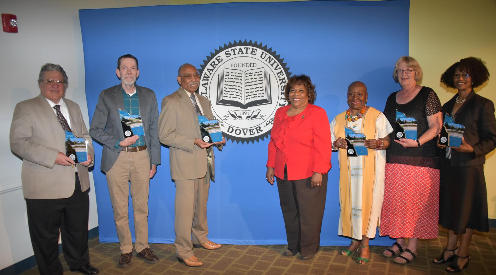 (L-r) 2018-2019 retirees Dr. Peter DiMaria, Dr. Andrew Lloyd, Dr. John Austin, University President Wilma Mishoe (who unretired herself to be the institution's CEO), Dr. Dolores Finger Wright, Dr. Janet Hill and Dr. Sheridan Quarless Kingsberry.