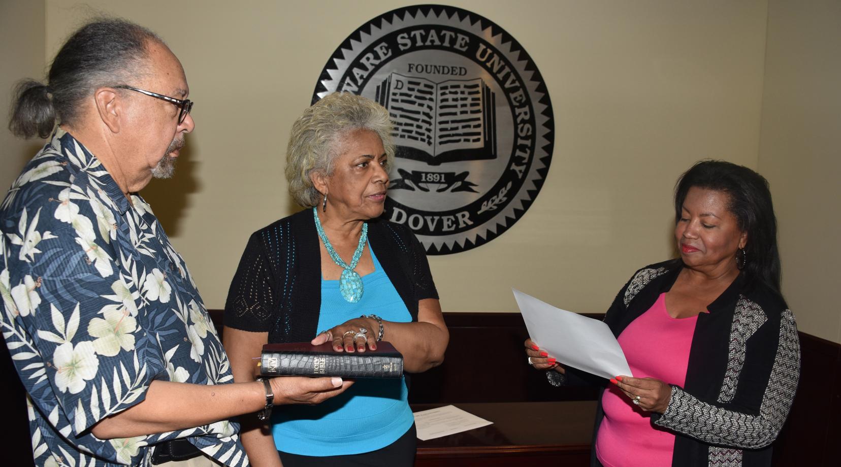 <p>J. Cagney France, fiance of Esthelda Parker Selby, center, holds the bible as she is sworn in as a Board of Trustees member by Board Chairperson Devona Williams.</p>