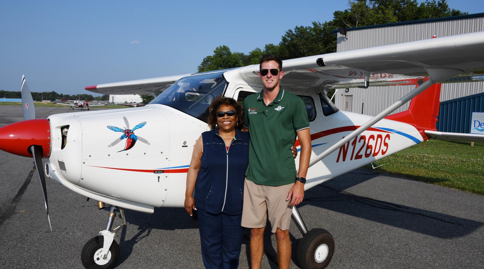 <p>DSU President Wilma Mishoe poses with Aviation Program graduate and current Instructor B. Lane DeLeon after flying into the Delaware Air Park on the first aircraft of a new fleet planes for the University.</p>