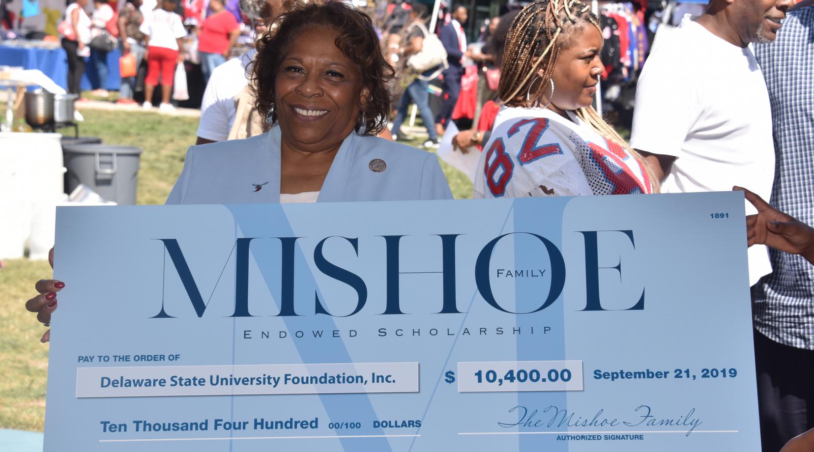 University President Wilma Mishoe holds a display check on behalf of her family that signals the establishment of the Mishoe Endowed Scholarship.