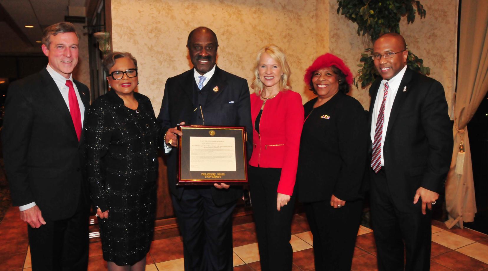 (L-r) Gov. John Carney, Rev. Dr. Jessica Kendall Ingram and her husband Bishop Gregory G.M. Ingram, Lt. Gov. Bethany Hall-Long, DSU Board of Trustees member Wilma Mishoe and DSU President Harry L. Williams, who presented the Ingrams with commendation from DSU.