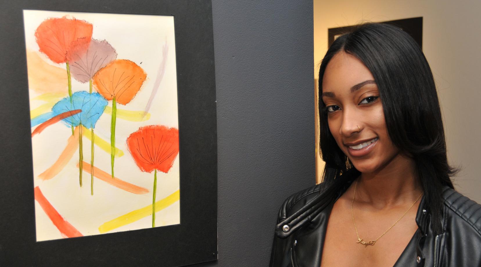 Kayla Redman stands beside her painting entitled "Flowers," which is one of three of her works on exhibition in the Art Student Honors Exhibition