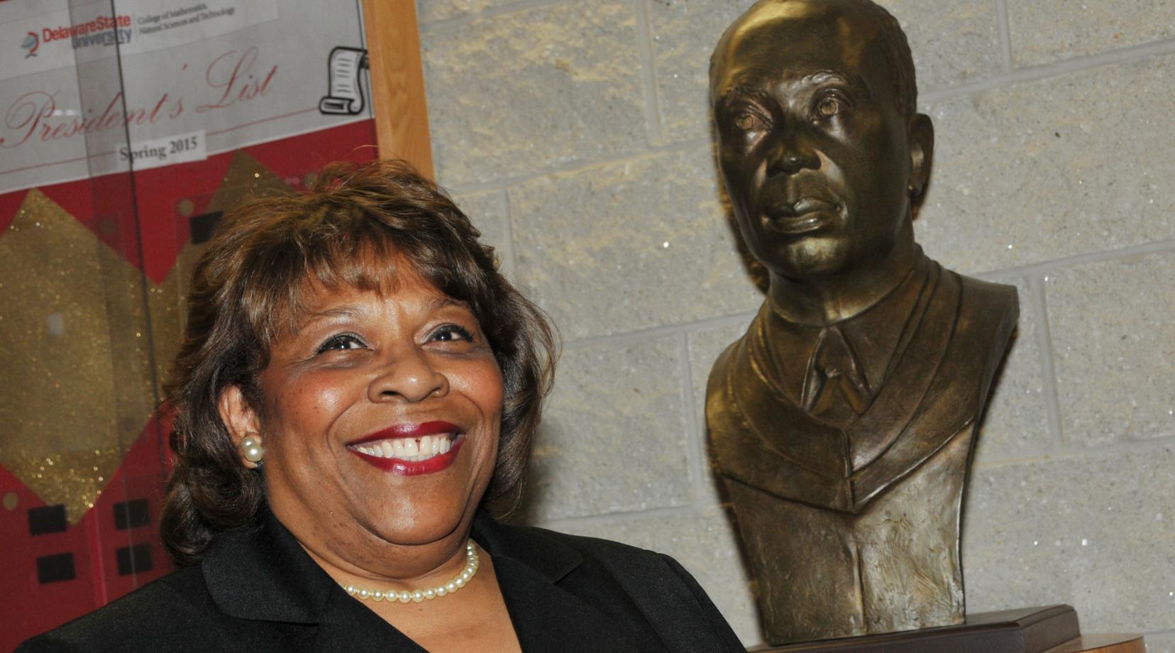 Dr. Wilma Mishoe, newly elected chairperson of the DSU Board of Trustees, stands next to the sculpture bust of her father Dr. Luna I. Mishoe, who was the president of then-Delaware State College from 1960-1987. Dr. Mishoe is the first woman to serve as the chair of the University's Board of Trustees.