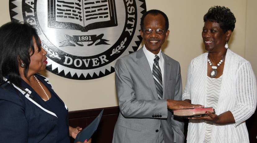 <p>Harold Stafford (center) takes the Board of Trustees oath from Board Interim Chair Devona Williams (l) while his wife Velvia looks on.</p>
